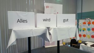 Photo einer Ausstellung auf einer Konferenz mit Kisten mit der Beschriftung "alles wird gut".