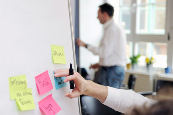 Foto von einem Flip Chart auf dem bunte Post its kleben, welche noch beschrieben werden