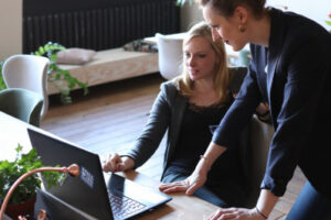 Foto von zwei Frauen, welche auf einen Laptop gucken