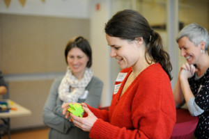 Foto von zwei Frauen, eine im Vordergrund mit Lego in den Händen, eine mit verschränkten Armen im Hintergrund als Symbol-Bild für einen Team-Workshop