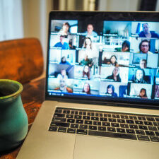 Foto mit einem Laptop wo ein Videochat zu sehen ist mit ganz vielen Teilnehmern